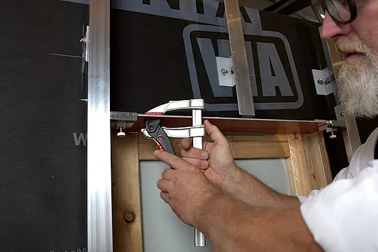 Der Zuschnitt der Aluminium Verbundplatte wird mit einer Schraubzwinge fixiert.