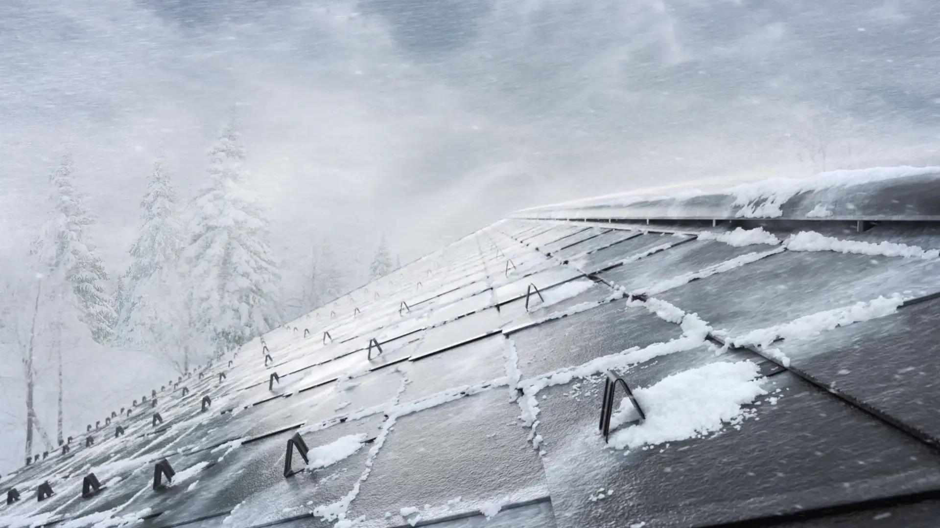 Frühjahrskampagne 2026 von PREFA – Ein schneebedecktes Dach mit Aluminiumplatten, das in einem winterlichen Sturm steht. Im Hintergrund sind verschneite Bäume sichtbar. Die Platten sind mit Schneerändern bedeckt, und die Dachrinnen sind teilweise von Schnee umgeben.