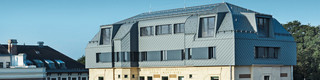Saniertes Dachgeschoss der BOKU Wien mit PREFA Dach- und Wandrauten 29 × 29 in P.10 Hellgrau