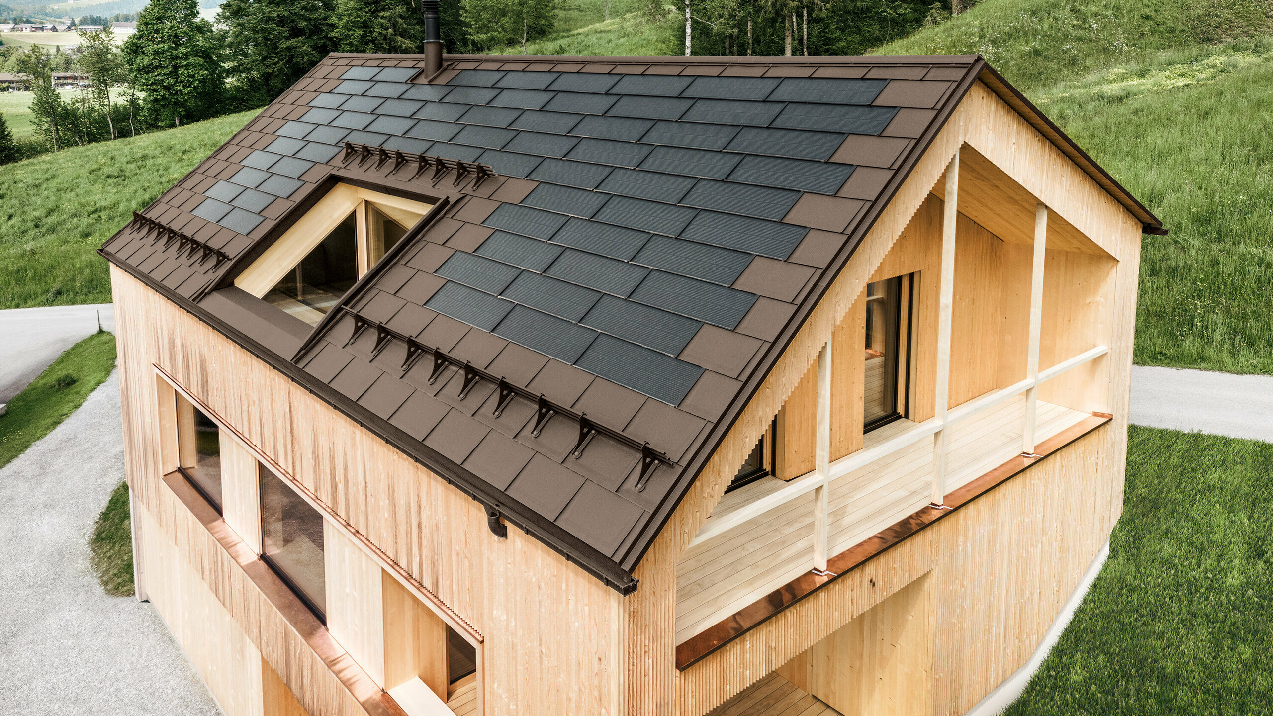 Einfamilienhaus im österreichischen Ort Egg mit der PREFA Solardachplatte und der Dachplatte R.16 in Braun, kombiniert mit einer Holzfassade
