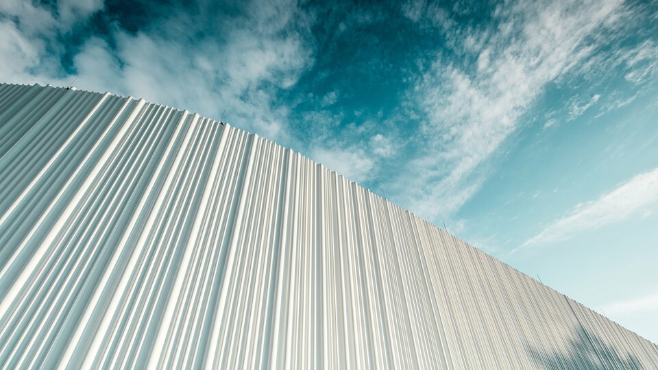 Atemberaubende Architektur mit weißer PREFA Aluminiumfassade im Walter Business-Park bei Wien. Die Fassade aus maßgefertigten Individualprofilen erzeugt durch ihren fließenden Wellencharakter ein faszinierendes Spiel aus Licht und Schatten. Drei unterschiedliche Profilformen sorgen für eine außergewöhnliche Tiefenwirkung und verleihen dem Gebäude eine stilistisch klare und zugleich dynamische Optik. Die langlebige, witterungsbeständige PREFA Oberfläche kombiniert moderne Ästhetik mit funktionaler Perfektion – ein echtes Highlight zeitgenössischer Fassadengestaltung, das architektonische Qualität und technische Raffinesse sichtbar macht.