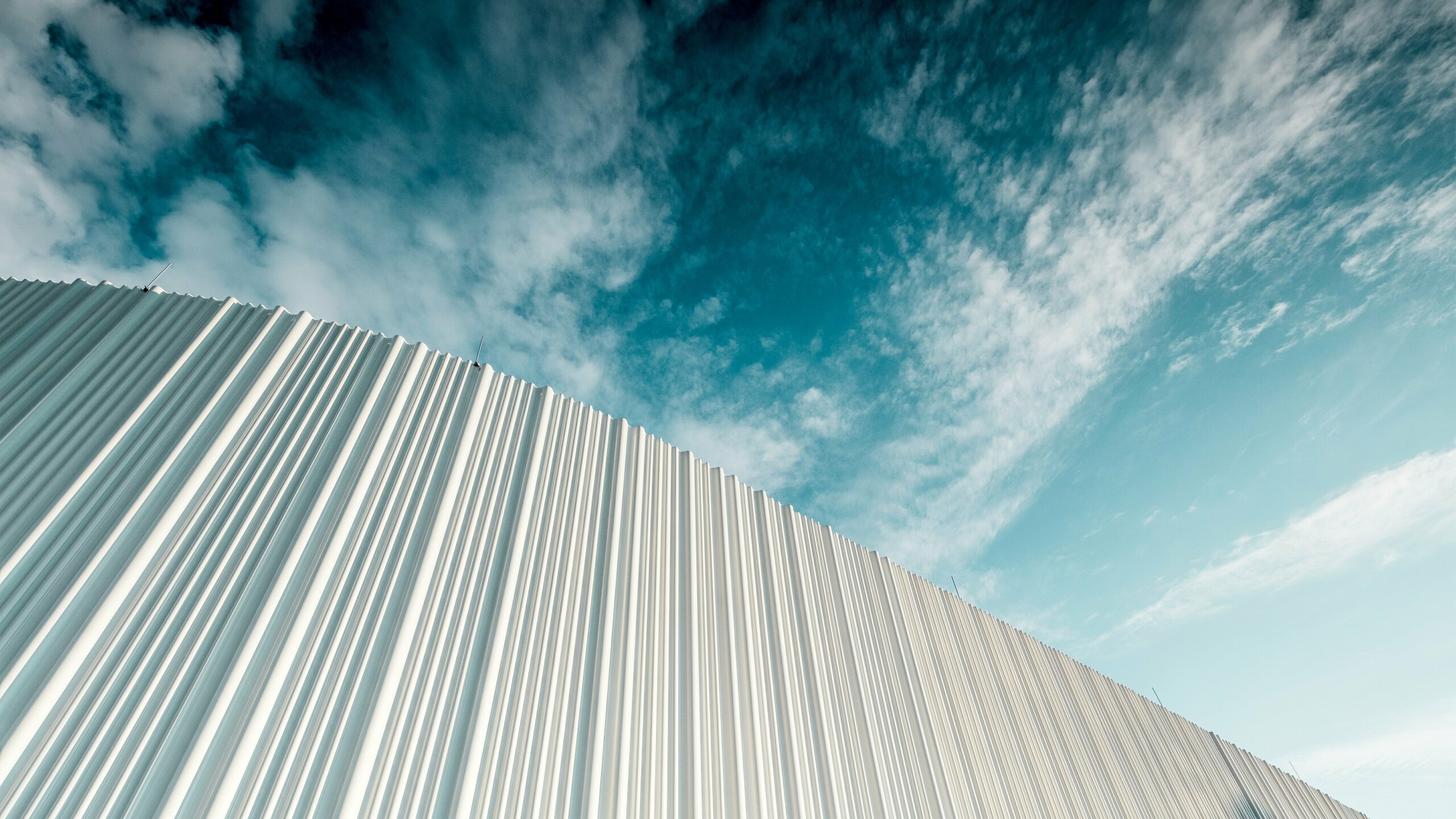 Atemberaubende Architektur mit weißer PREFA Aluminiumfassade im Walter Business-Park bei Wien. Die Fassade aus maßgefertigten Individualprofilen erzeugt durch ihren fließenden Wellencharakter ein faszinierendes Spiel aus Licht und Schatten. Drei unterschiedliche Profilformen sorgen für eine außergewöhnliche Tiefenwirkung und verleihen dem Gebäude eine stilistisch klare und zugleich dynamische Optik. Die langlebige, witterungsbeständige PREFA Oberfläche kombiniert moderne Ästhetik mit funktionaler Perfektion – ein echtes Highlight zeitgenössischer Fassadengestaltung, das architektonische Qualität und technische Raffinesse sichtbar macht.