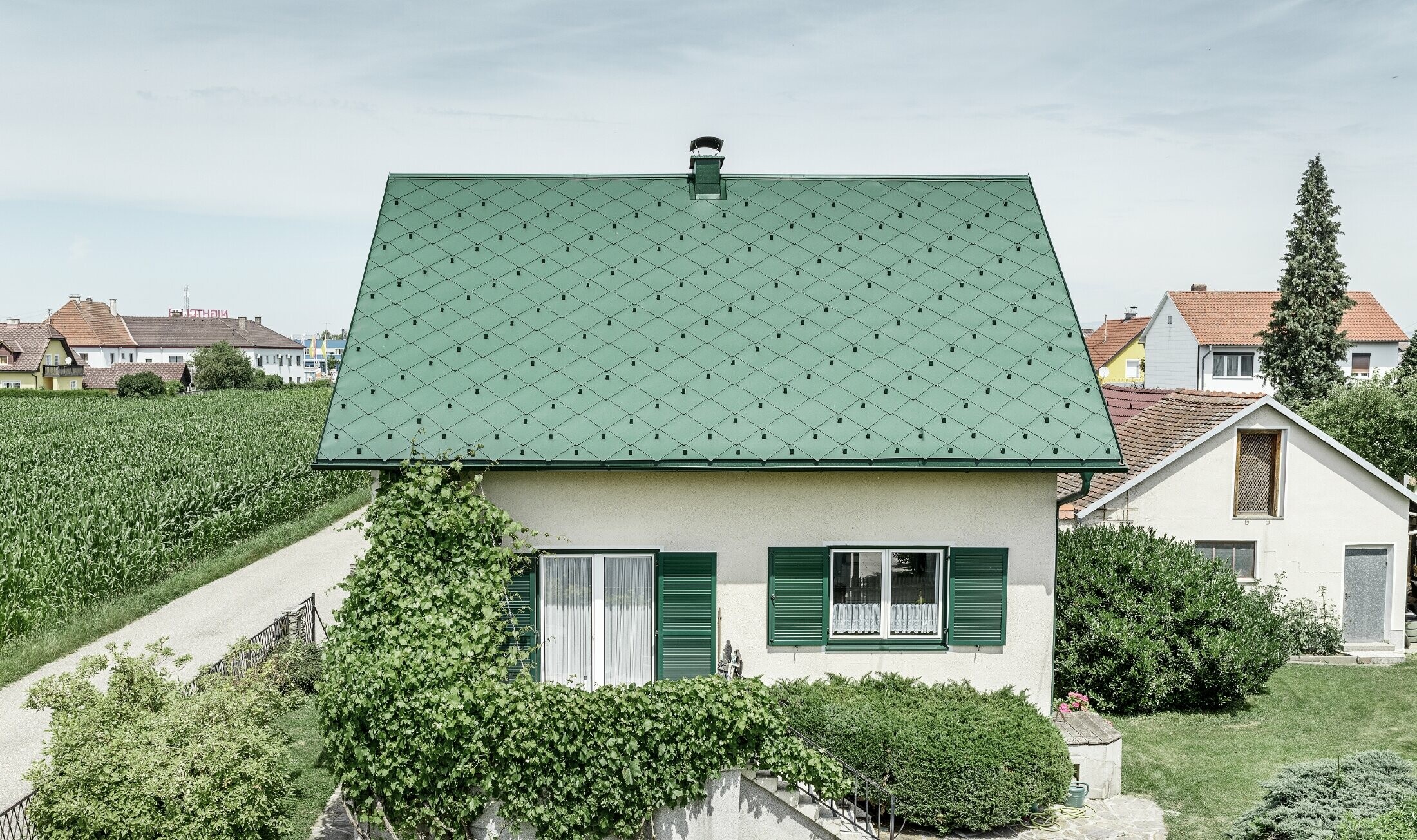 Klassisches Einfamilienhaus mit Satteldach mit einer Dacheindeckung aus Aluminium von in moosgrün mit grünen Fensterläden. Das Dach wurde mit PREFA Dachrauten 44 × 44 in P.10 Moosgrün eingedeckt.