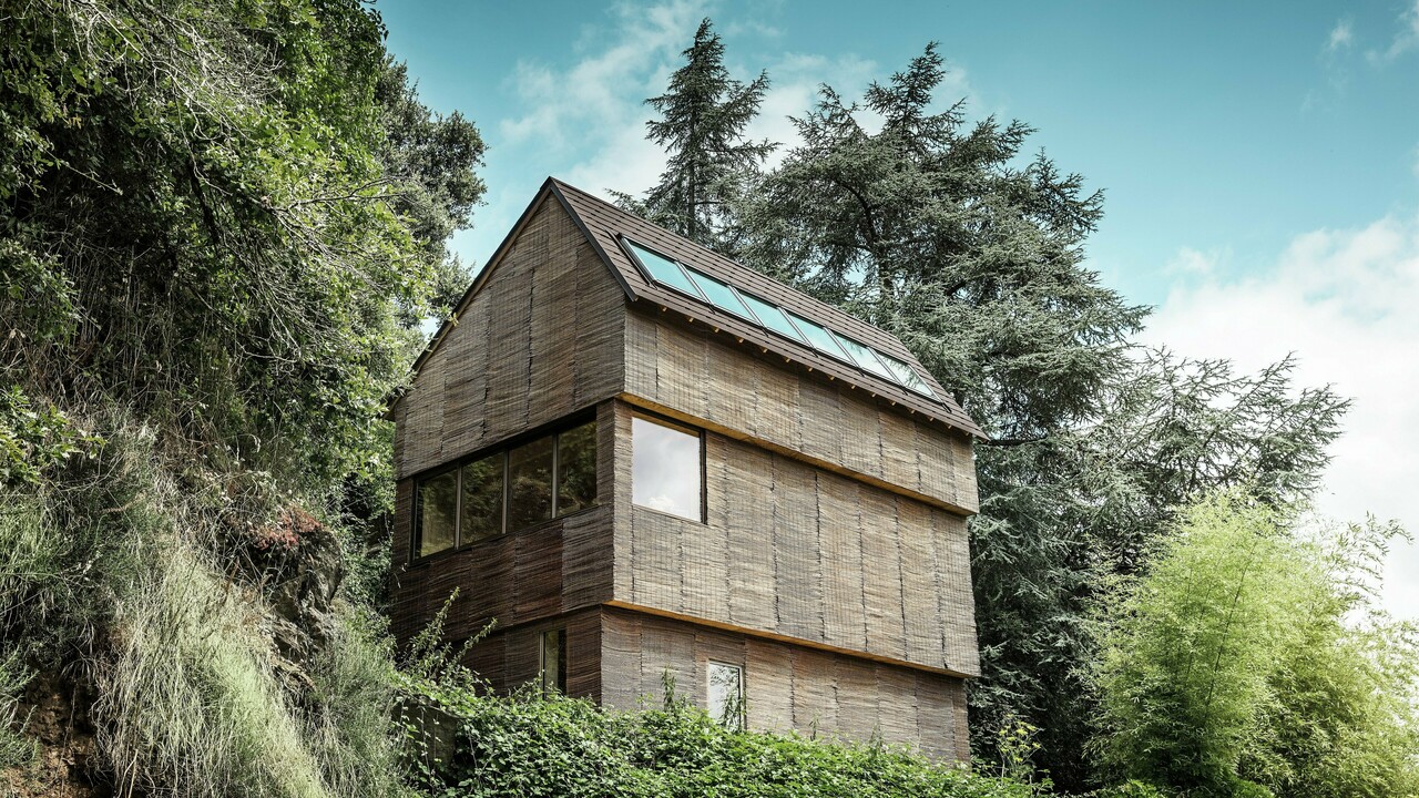 Ein Haus im Westen Frankreichs mit PREFA-Dachschindeln in der Farbe P.10 Walnussbraun, gelegen an einem steilen Hang – ein modernes Design mit einer Fassade aus Weidenholz und einem energieeffizienten Dach.