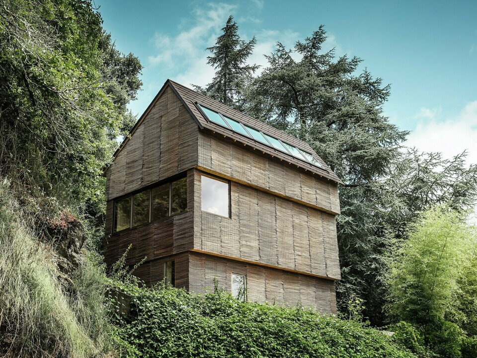 Haus im Westen Frankreichs mit PREFA Dachschindeln in P.10 Nussbraun auf steilem Hügel – modernes Design mit Weidenfassade und energieeffizientem Dach.