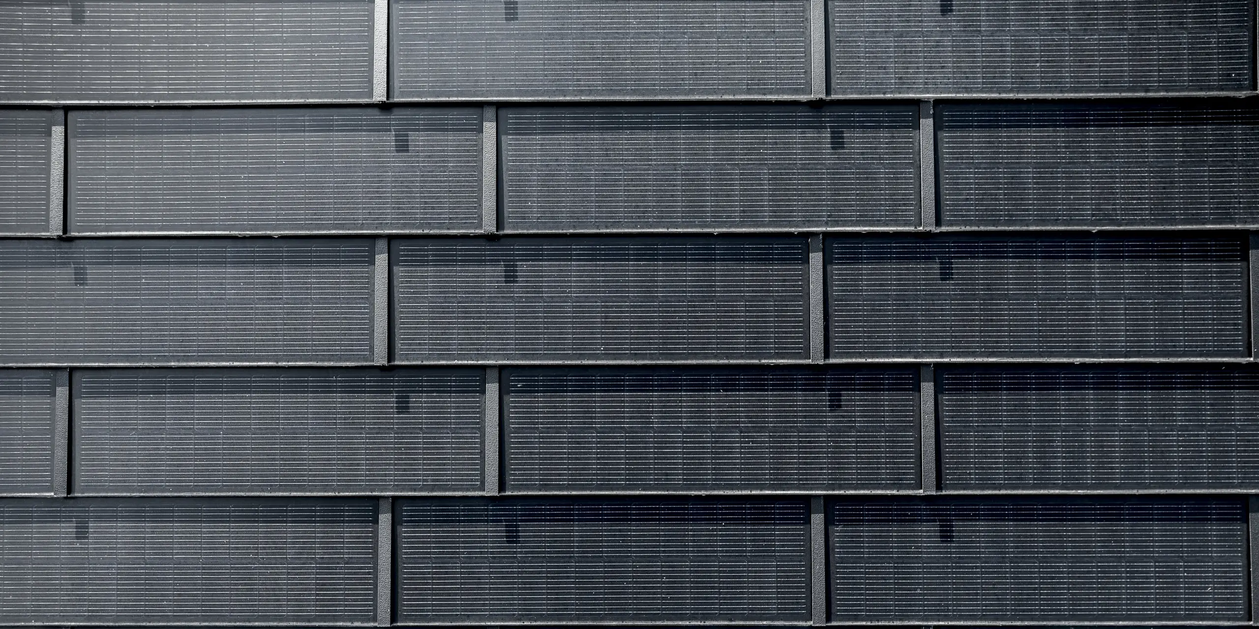 Nahaufnahme von präzise verlegten PREFA Solardachplatten mit integrierten Photovoltaikzellen. Die exakte Anordnung der Aluminiumplatten mit innovativer Photovoltaik-Technologie verbindet modernes Design mit nachhaltiger Energiegewinnung. Die robuste PREFA Lösung überzeugt auch bei anspruchsvollen Architekturkonzepten.