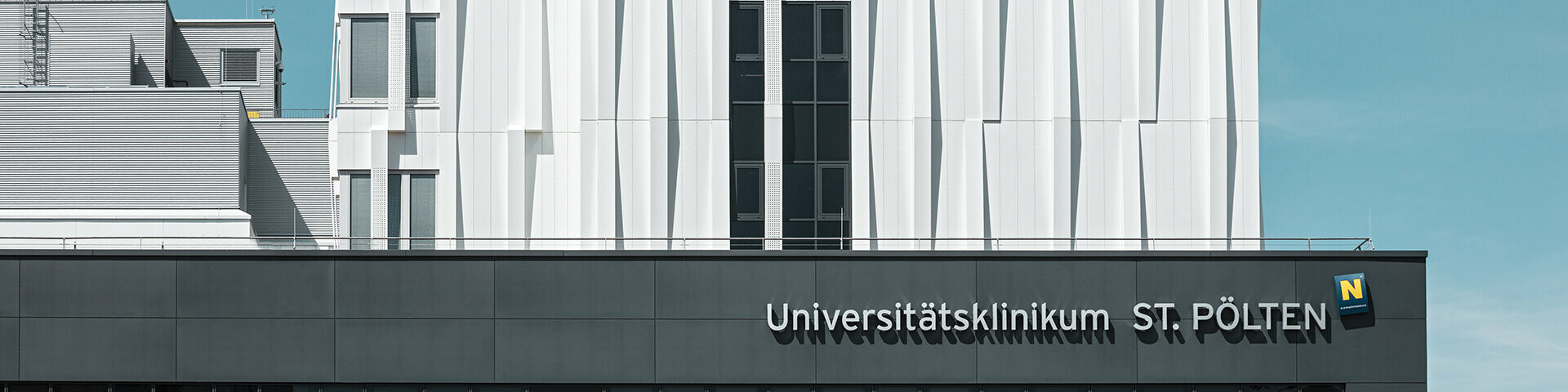 Frontansicht des Universitätsklinikums St. Pölten, Österreich. Im Hintergrund erhebt sich die robuste, reinweiße Aluminiumfassade.