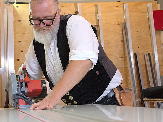 Tom Weiß sägt die angezeichneten Verbundplatten mittels Kreissäge auf Maß.