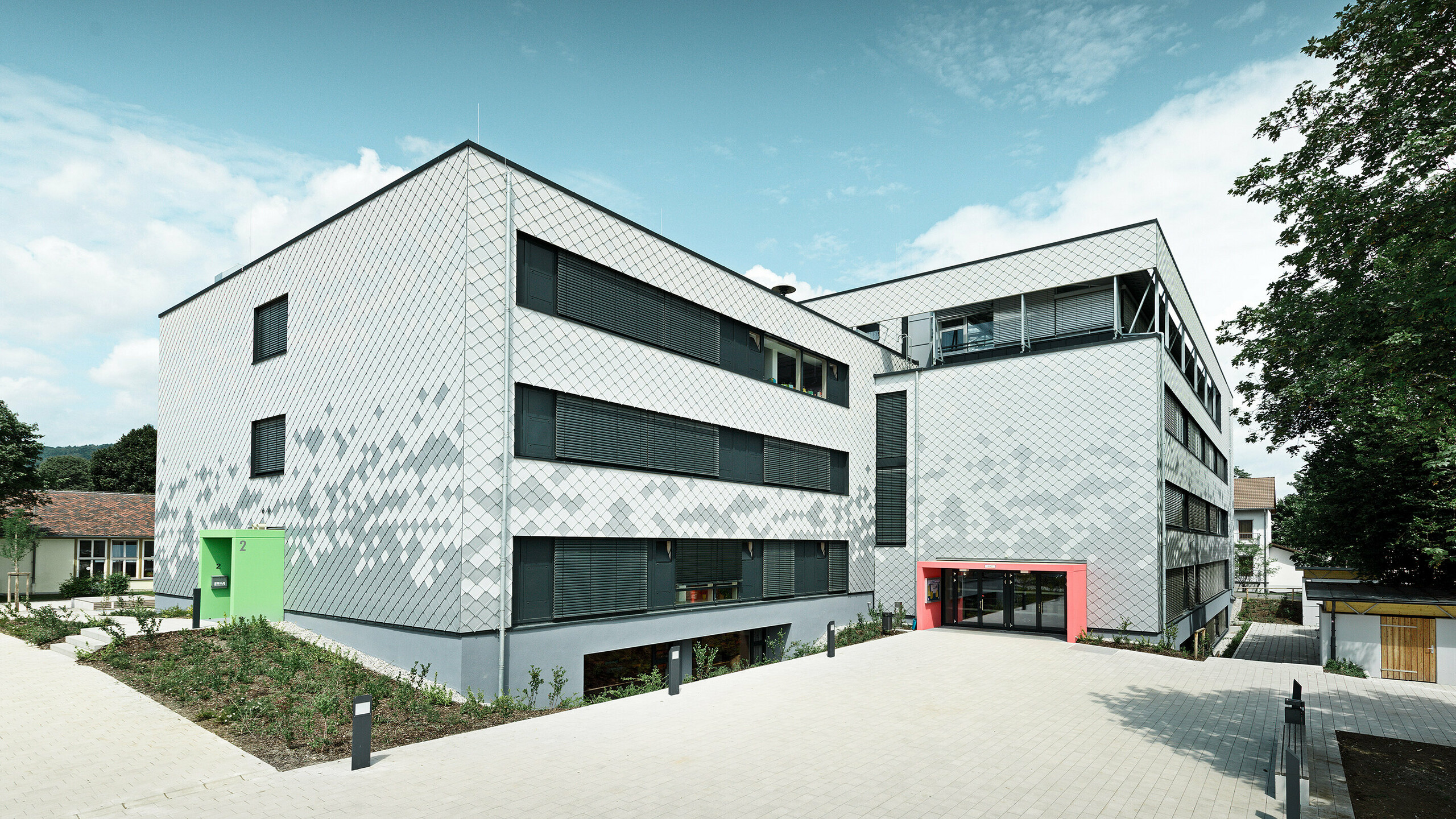 Deutsche Mittelschule mit neuer Fassade, verkleidet mit PREFA Wandrauten in drei verschiedenen Farben