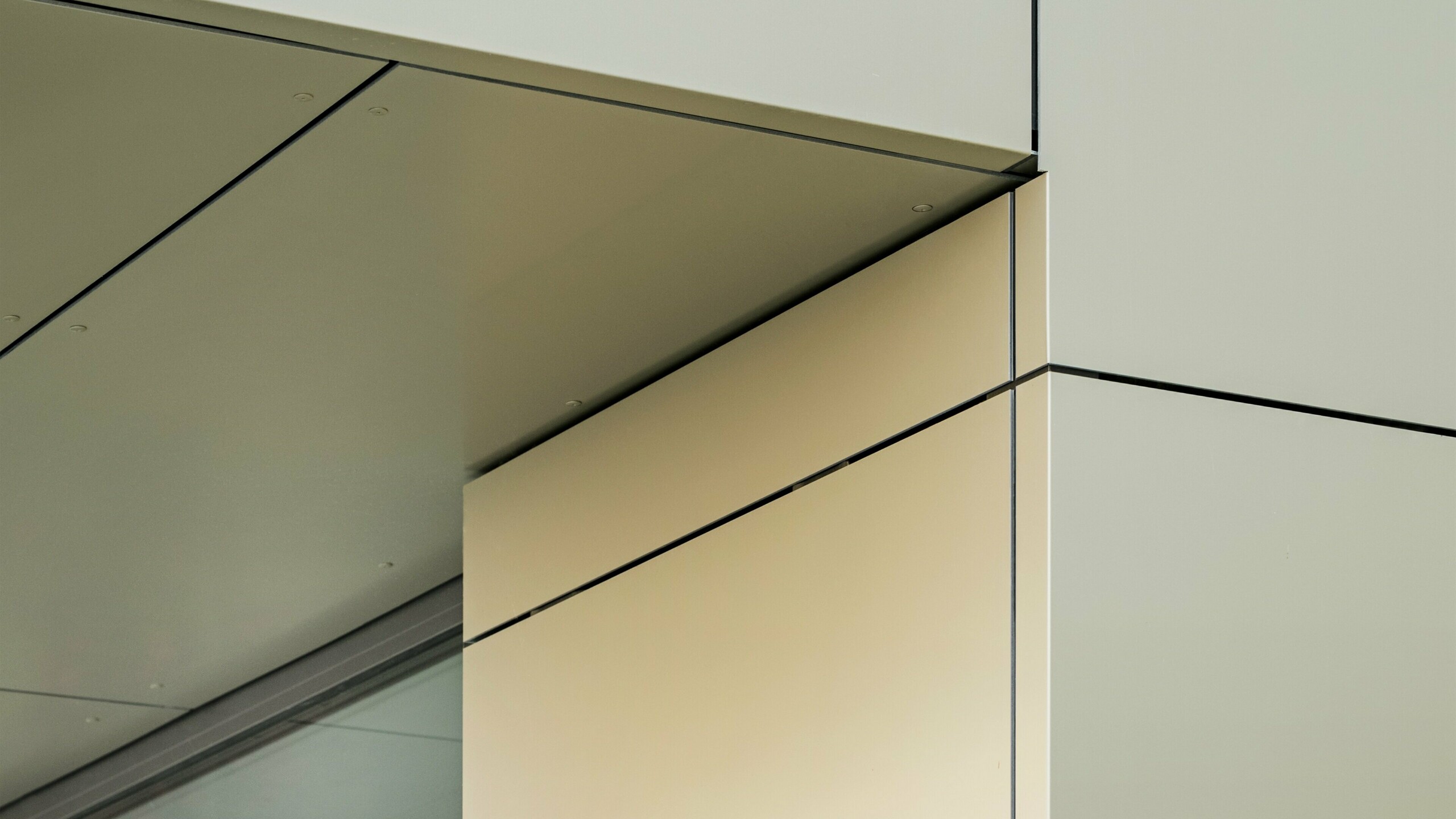 Detailaufnahme der Fassade des Rathauses in Alzenau, die die präzise Kante und Übergänge der Aluminium-Verbundplatten von PREFA hier in der Farbe bronze zeigt. Die Platten sind perfekt aneinandergefügt, wodurch eine klare, moderne Linienführung entsteht. Der metallische Glanz der Platten wird durch die feinen Fugenlinien und die minimalistischen Details der Architektur betont, was der Fassade ein elegantes und zeitgemäßes Aussehen verleiht.