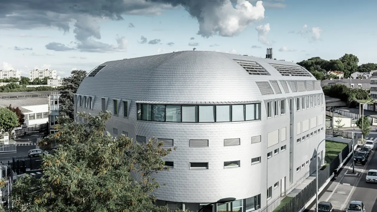 Die abgerundete Gebäudefläche wurde sowohl am Dach als auch auf der Fassade mit Aluminiumschindeln von PREFA in Silbermetallic eingedeckt. 