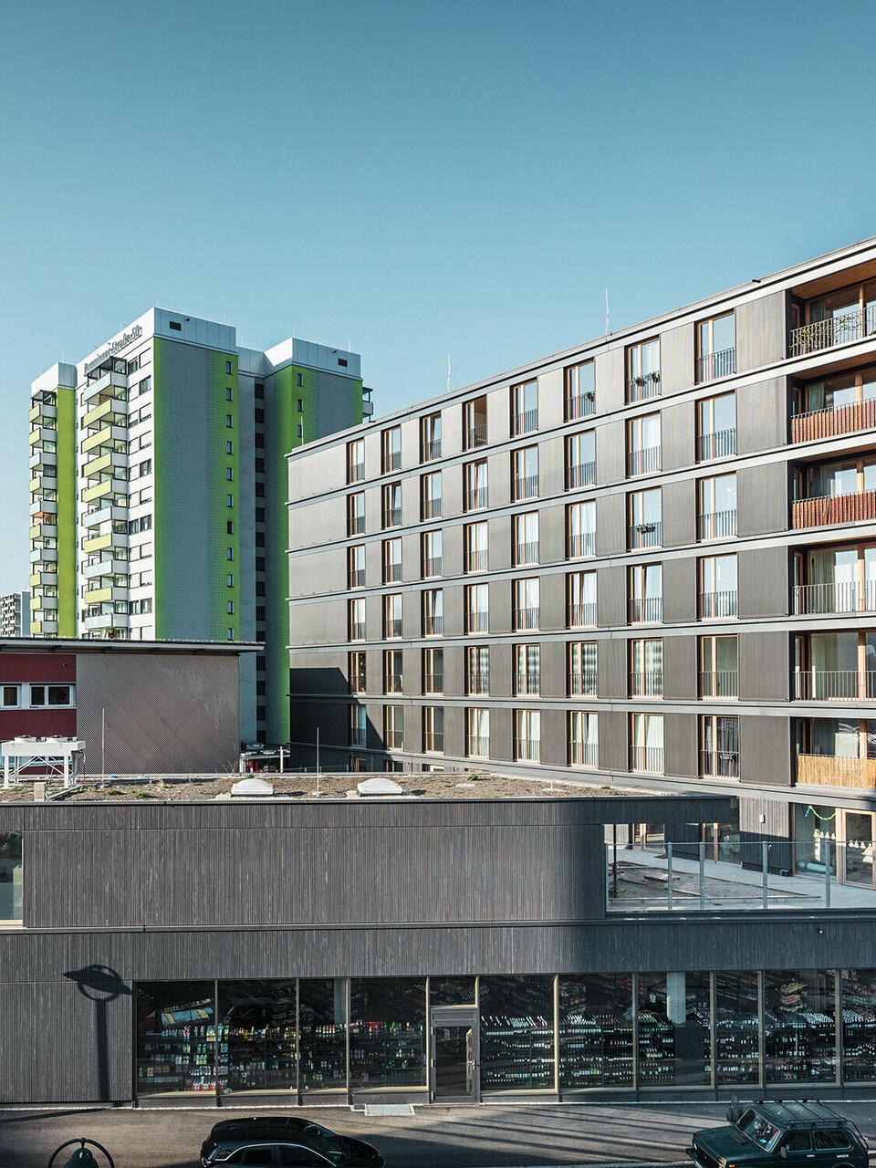 Blick auf den schwarzgrauen Multifunktionsbau Buggi 52 mit seiner gebauten Umgebung von der Straße aus. 