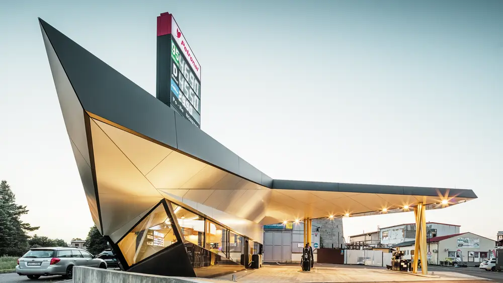 Seitlicher Blick auf die dynamische, mit Aluminium bekleidete Tankstelle von Architekt Daniel Zerzán: Etliche Dreiecke und Trapeze strukturieren die Fassade.