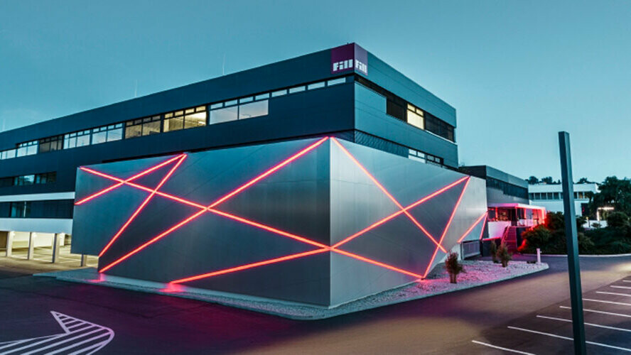 Fassade eines Firmengebäudes mit einem Knick in der Wand, die mit PREFA Verbundplatten aus gebürstetem Alu verkleidet wurde.