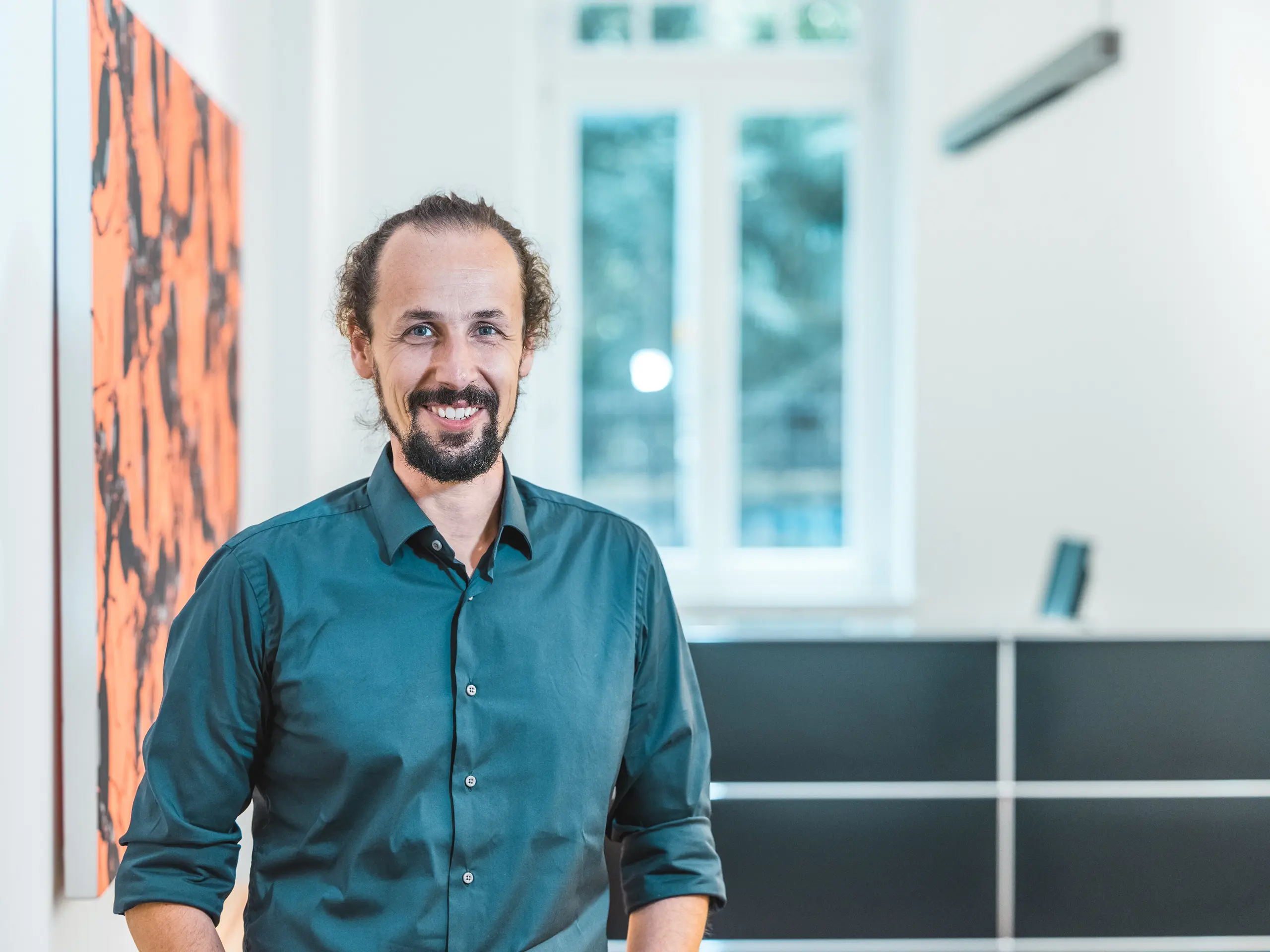 Porträt des Architekten Gianfranco Berardesca in einem modernen Innenraum. Der Projektleiter des Büros Höller & Klotzner Architekten begleitete die Realisierung des Bildungszentrums Riffian in Südtirol. Das ausgezeichnete PREFARENZEN-Objekt wurde mit PREFA-Dachrauten in der Größe 44 × 44 und der Farbe P.10 Bronze umgesetzt und steht für präzise Planung, Architekturqualität und Südtiroler Handwerkskunst.