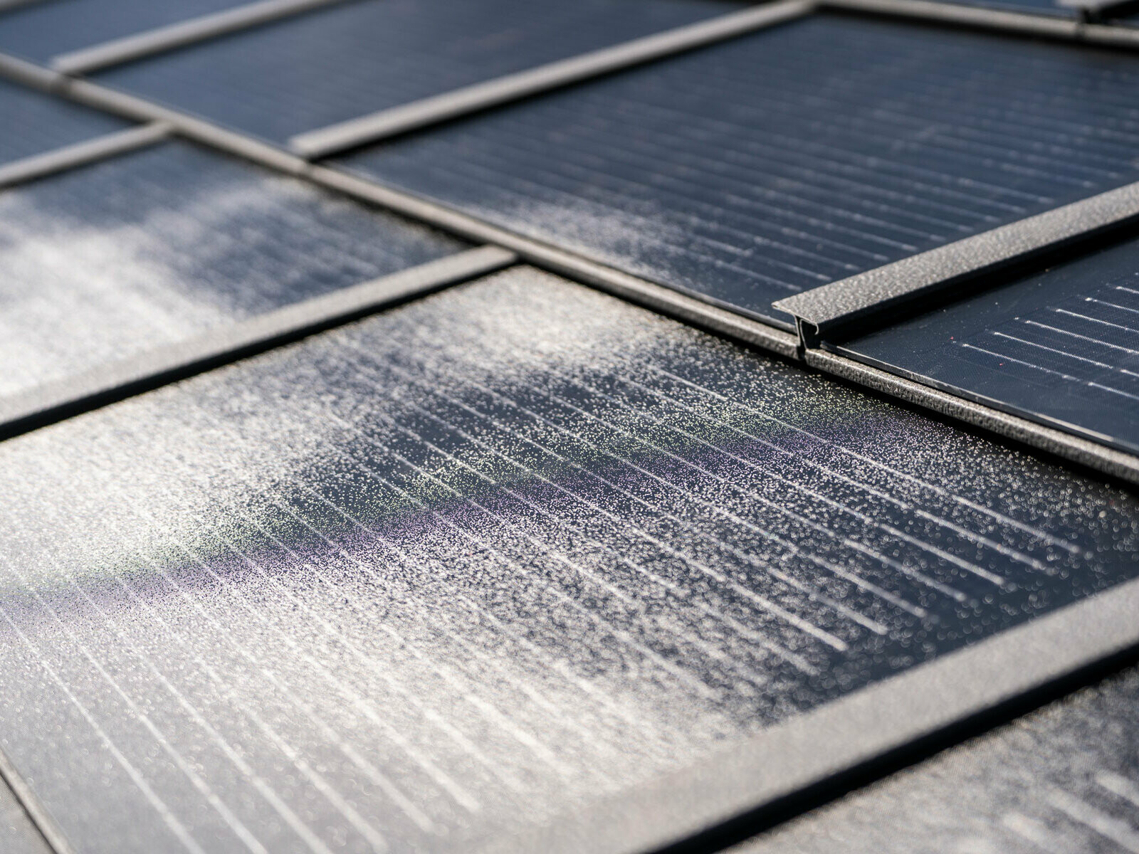 Nahaufnahme der verlegten PREFA Solardachplatte klein und Dachplatte R.16 in der Farbe P.10 Dunkelgrau