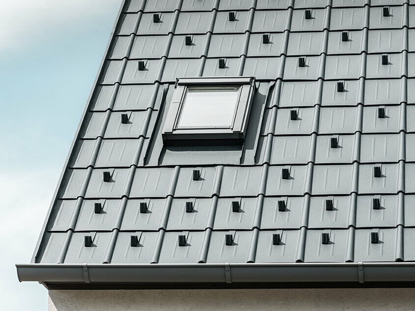 PREFA Dachplatte mit Schneestoppern in Anthrazit verlegt mit eingebautem Dachfenster und PREFA Dachrinne. Dachfläche mit PREFA Blechdach