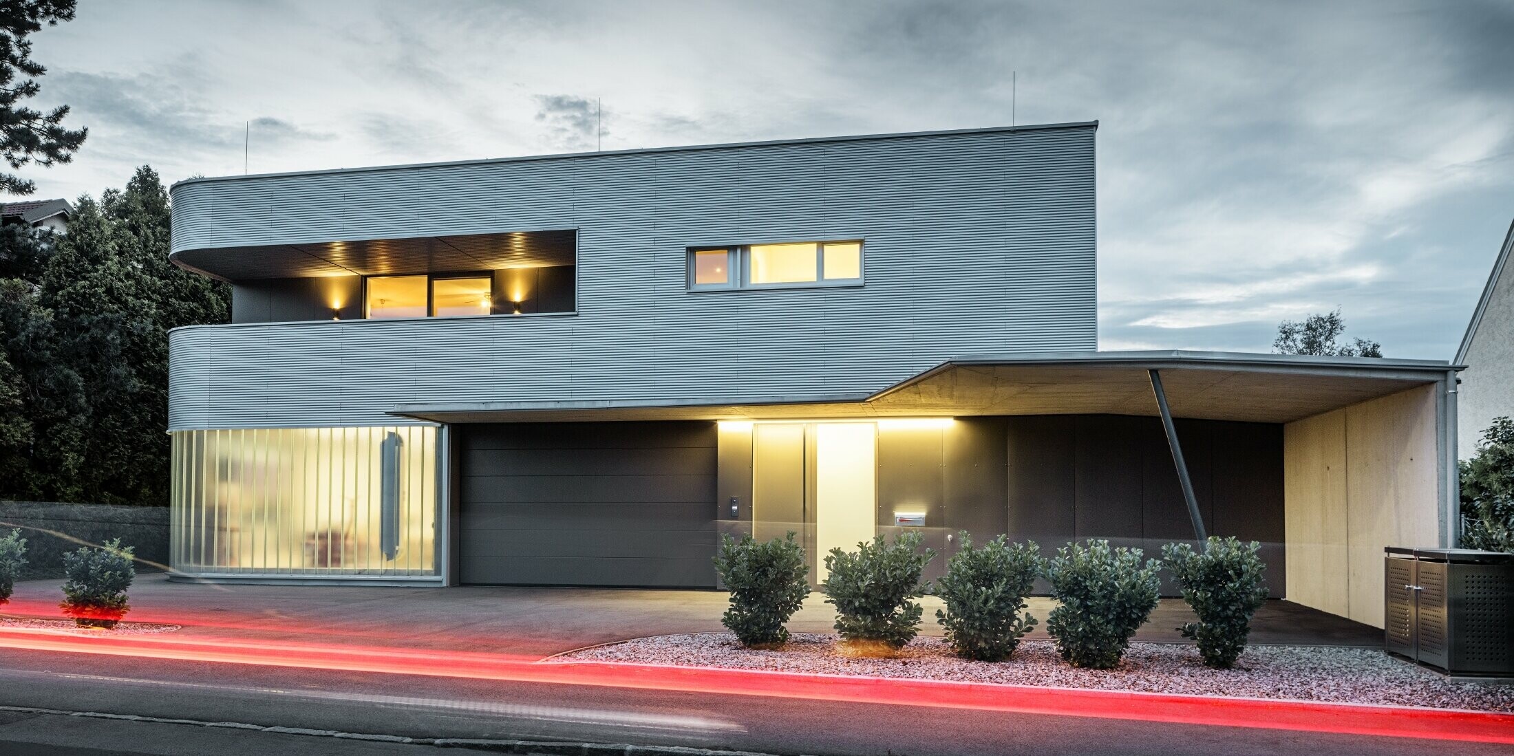 Modernes Wohnhaus mit naturblanker Fassade aus der PREFA Profilwelle mit Garage, bei Abendlicht fotografiert