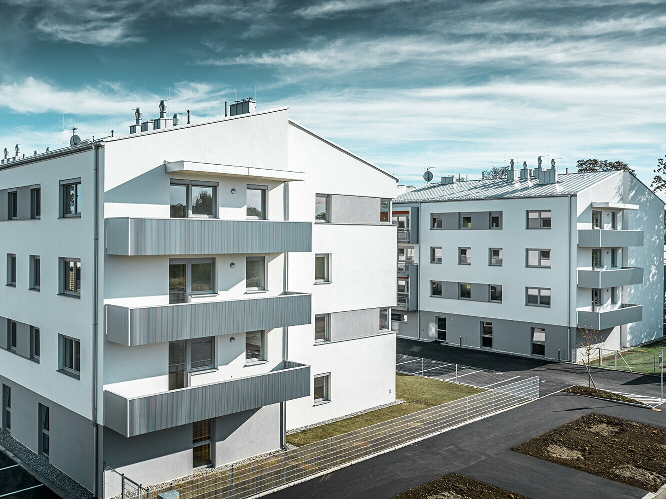 Moderne Wohnhausanlage mit weißer Fassade und Balkonen mit PREFA Zackenprofil in Silbermetallic