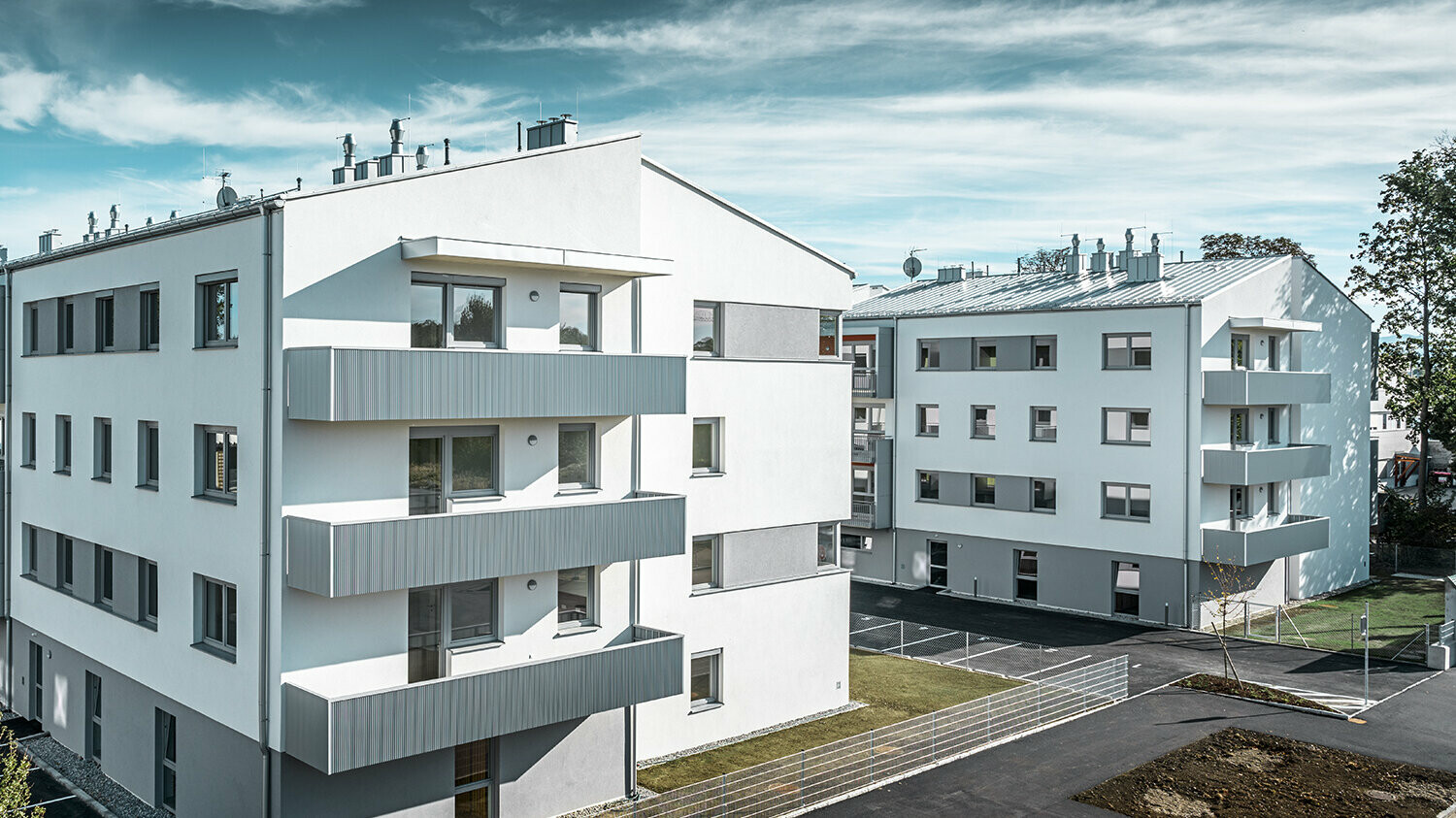 Moderne Wohnhausanlage mit weißer Fassade und Balkonen mit PREFA Zackenprofil in Silbermetallic