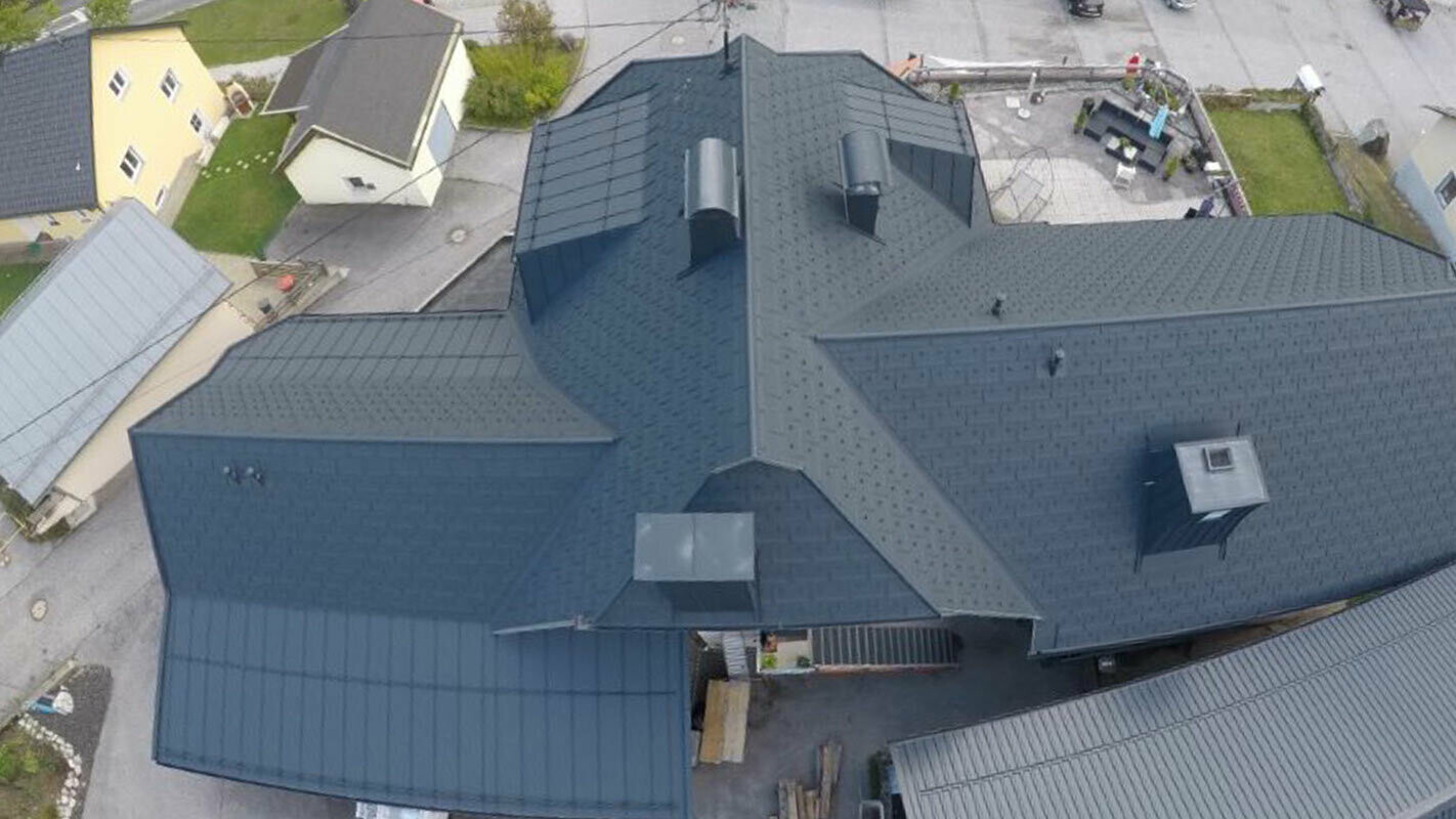 Dachsanierung einer großen Dachfläche mit vielen Details - Kehlen, Gauben und Kamine. Das Dach ist mit der Alu Dachplatte R.16 von PREFA in Anthrazit eingedeckt.