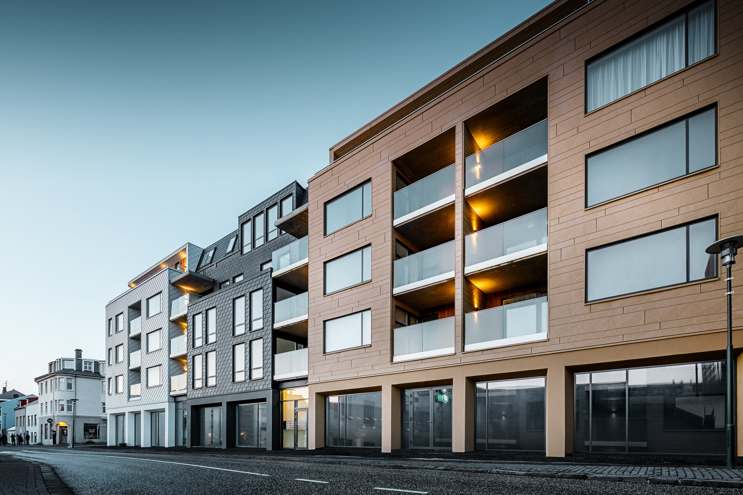 Seitliche Vorderansicht des Gebäudes - verkleidet mit Schindeln, Rauten und Siding.X in den Farben Weiß, Anthrazit und Sandfarben.