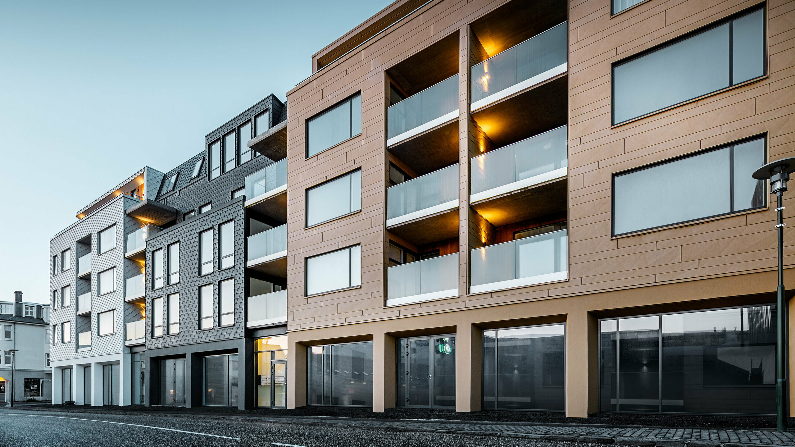 Seitliche Vorderansicht des Gebäudes - verkleidet mit Schindeln, Rauten und Siding.X in den Farben Weiß, Anthrazit und Sandfarben.