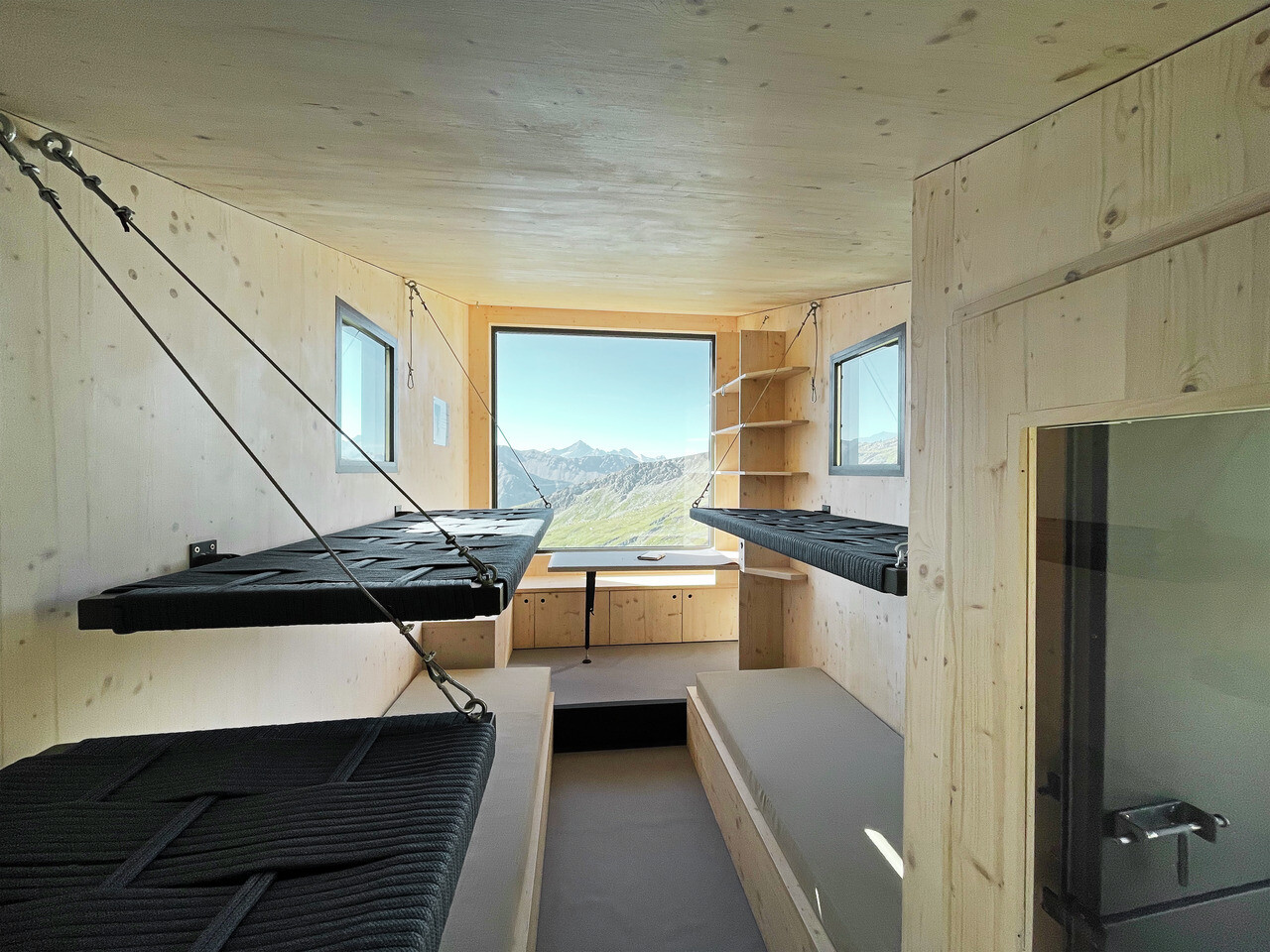 Innenansicht der Schutzhütte. Ein großes Fenster bietet einen tollen Ausblick.