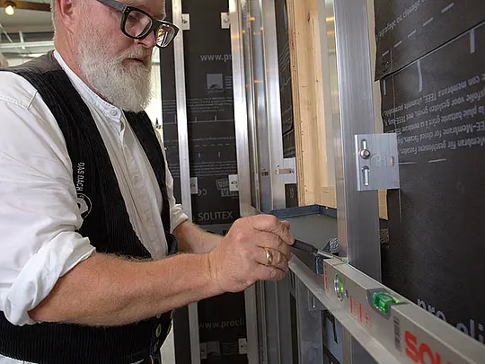 PREFA-Techniker Tom Weiß misst die Höhe des Fensterblechs ab.