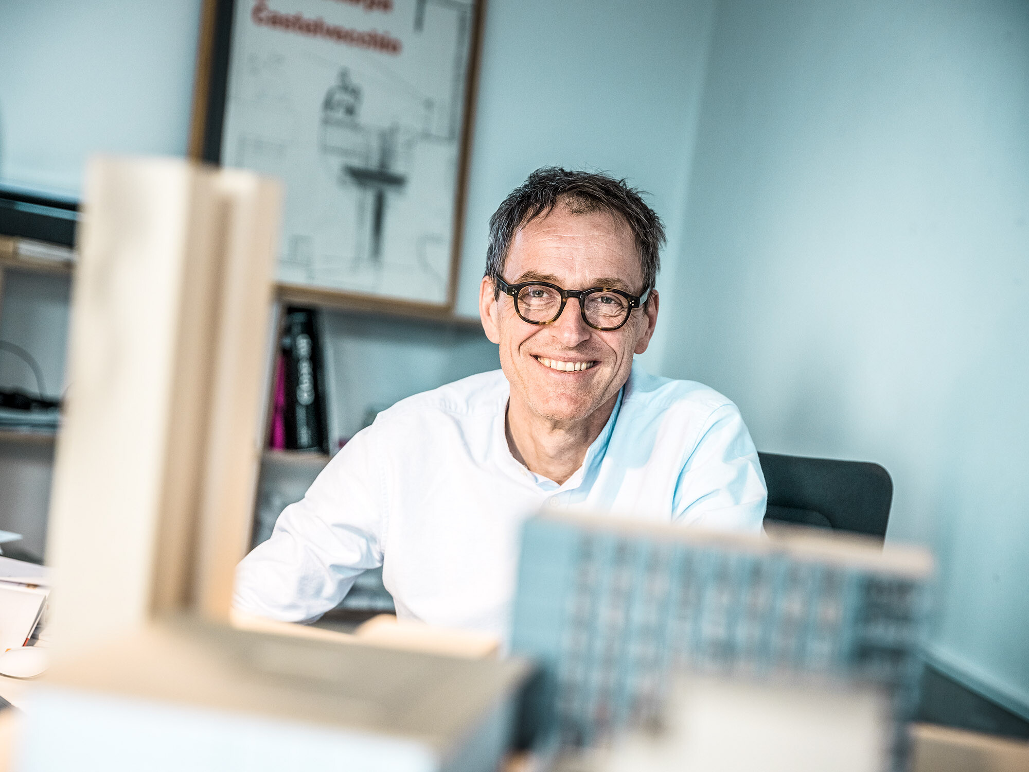 Portrait des leitenden Architekten Jochen Weissenrieder, lächelnd, in seinem Büro.