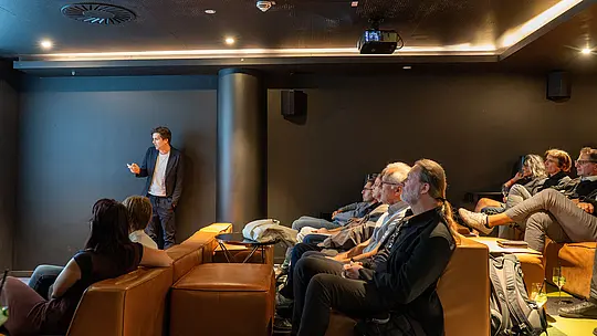 Beim PREFARENZEN Special Wien lauschen Gäste im modernen Kinosaal einem Vortrag über Architektur und nachhaltiges Bauen. Die weitläufige Aufnahme zeigt die konzentrierte Atmosphäre, gemütliche Sitzlandschaft und den direkten Austausch zwischen Referent und Publikum. PREFA verbindet innovative Aluminiumlösungen mit langlebiger Qualität, vielseitigem Design und zukunftsorientierten Baukonzepten.