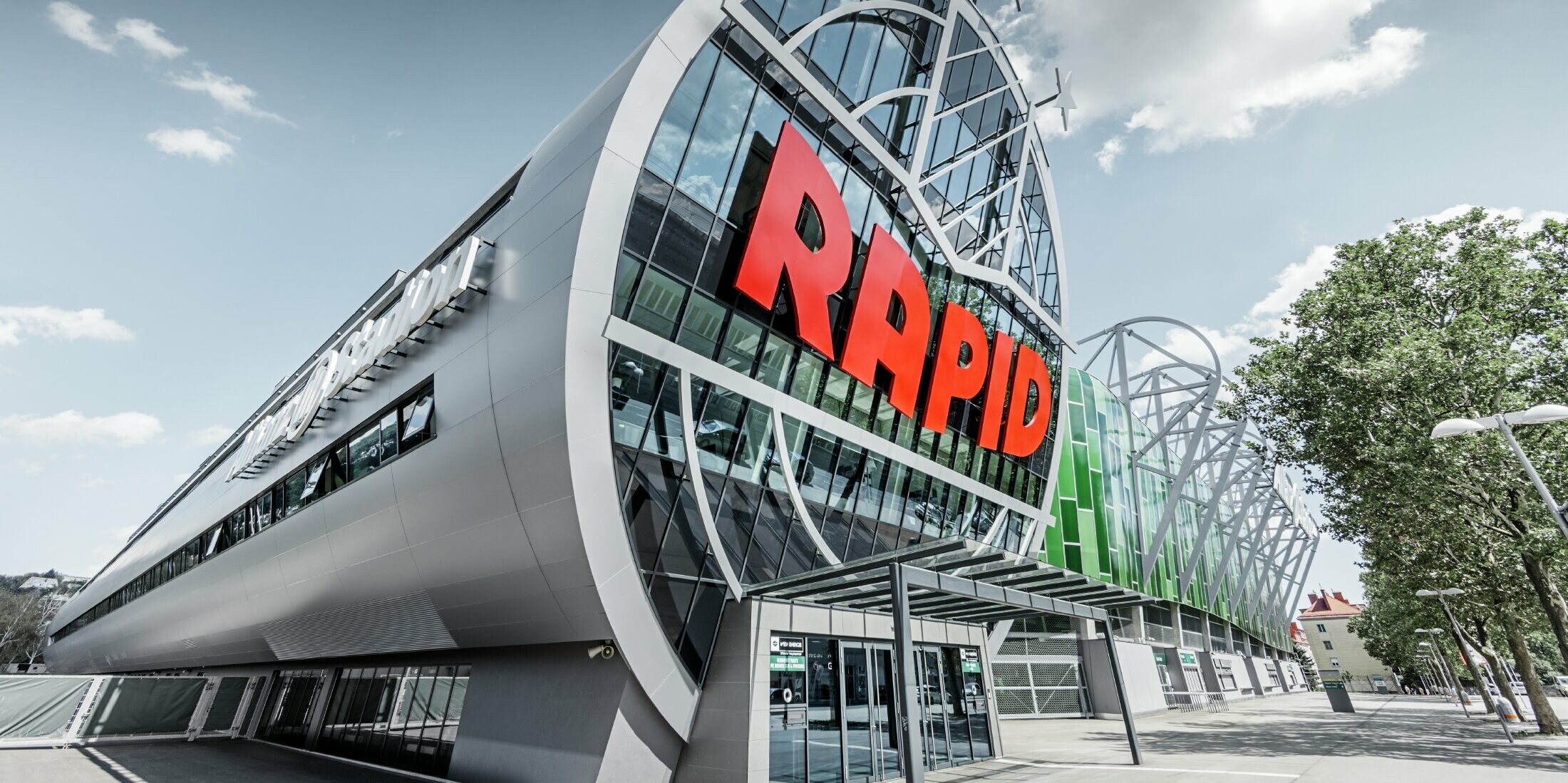 Der Eingang ins Allianz Stadion mit dem großen SK Rapid Wien Logo; Die Röhre mit der großen Glasfront ist mit der PREFA Aluminium Verbundplatte in Silbermetallic eingedeckt.