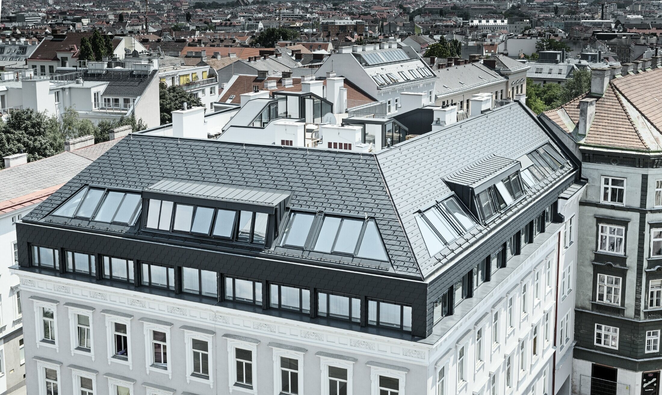 Vogelperspektive einer Wohnausanlage in der Wiener Mariahilferstraße - ausgebautes Dachgeschoss mit der PREFA Dachschindel in Anthrazit.