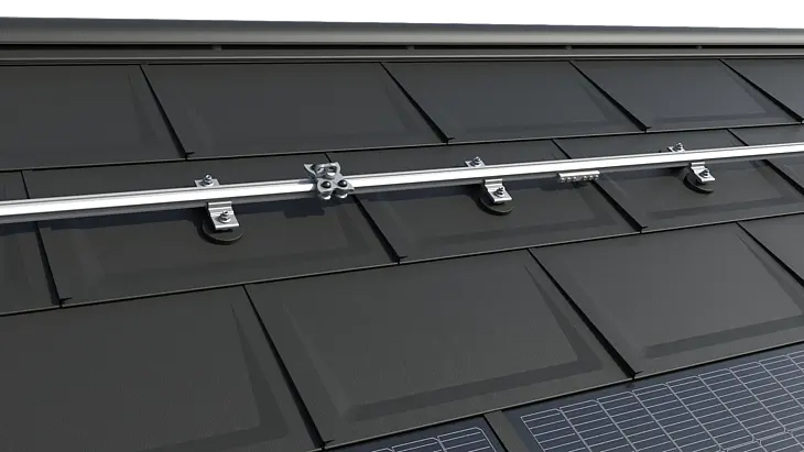 Das Bild zeigt das TAURUS Schienensystem von INNOTECH® auf einem PREFA Dach mit der bewährten Dachplatte R.16. Die Installation umfasst horizontale Führungsschienen und speziell entwickelte Gleiter, die eine sichere Dachbegehung und Wartung von Photovoltaikanlagen ermöglichen. Das System ist für alle PREFA Kleinformate geeignet und bietet eine zuverlässige Lösung für die Montage und Instandhaltung von PV-Anlagen. Von PREFA in Zusammenarbeit mit den Arbeitsschutz-Experten von INNOTECH® entwickelt, ist das Sicherungssystem nach EN 795 Typ A und D zertifiziert und für die Sicherung von zwei Personen ausgelegt. Am unteren Bildrand sind die innovativen PREFA Solardachplatten zu erkennen.