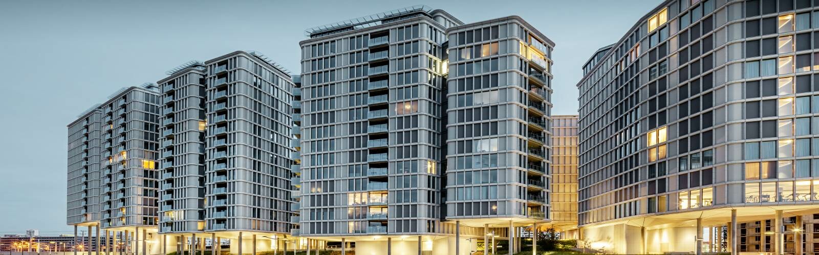 Vorderansicht der Belvedere Apartments am Abend. Die PREFA Profilwelle wurde mit Glas und Keramikelementen kombiniert