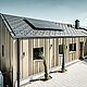 Architektonisch ansprechendes Einfamilienhaus, harmonisch in die Hügellandschaft eingebettet, mit einem hochwertigen PREFA Dachsystem in Form der Dachplatte R.16 in elegantem P.10 Anthrazit. Die Fassade zeichnet sich durch eine geschmackvolle Winkelfalzkonstruktion aus Falzonal in Lichtbronze aus, die das Gebäude mit einem warmen, metallischen Glanz umhüllt. Das Haus verfügt zudem über eine umweltfreundliche Komponente in Form von Solarmodulen, die diskret auf dem Dach integriert sind. Die PV-Anlage sowie die Gebäudehülle aus langlebigem Aluminium betonen das Engagement für nachhaltiges Bauen. Eine minimalistische Garage fügt sich nahtlos an das Hauptgebäude an, während die gepflasterte Einfahrt und sorgfältig platzierte Grünpflanzen das Bild eines modernen, ökologisch bedachten Zuhauses vervollständigen.