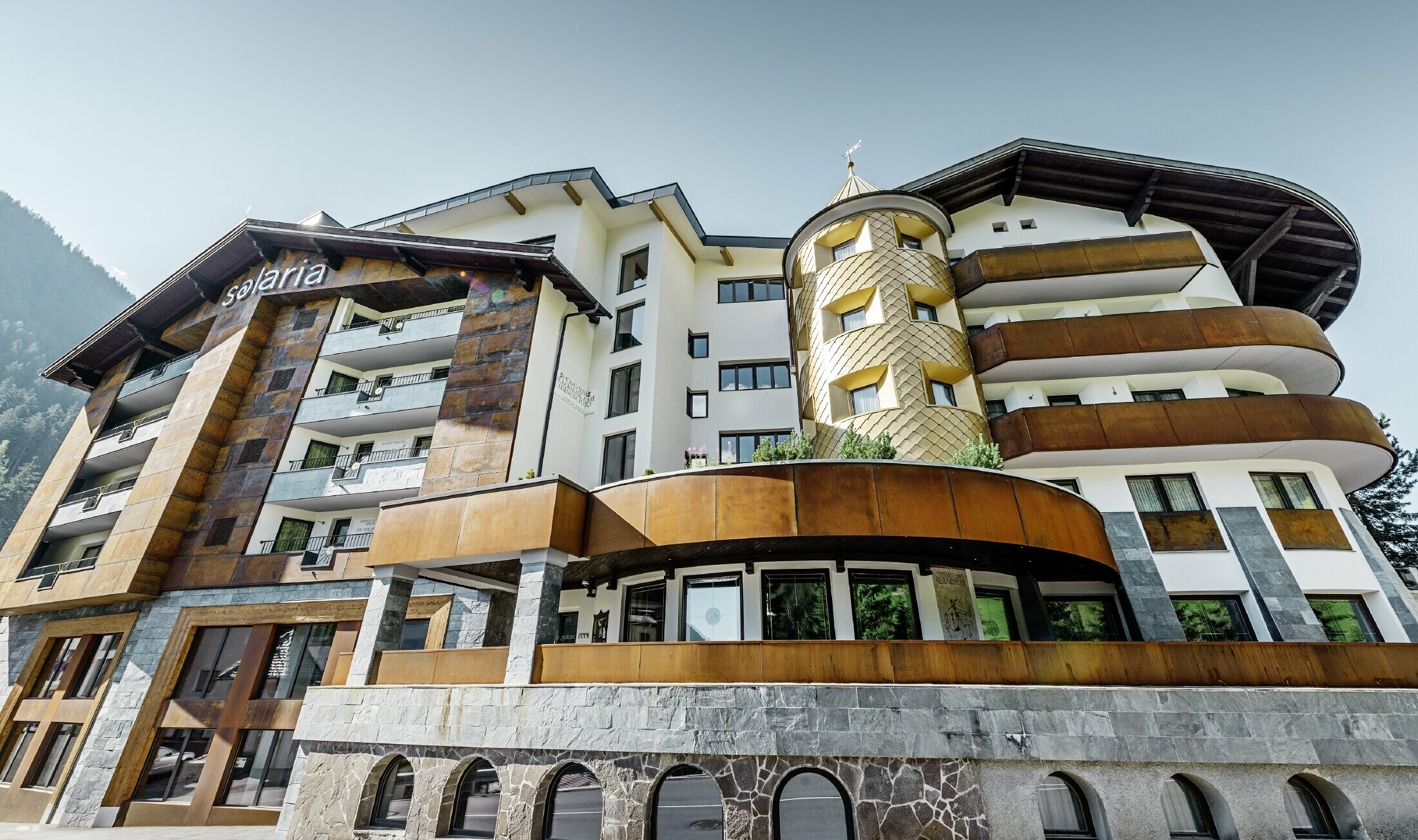 traditionelles Hotel in Ischgl mit Holzbalkonen und Holzfassade und einem Turm mit goldenen Alu-Rauten von PREFA