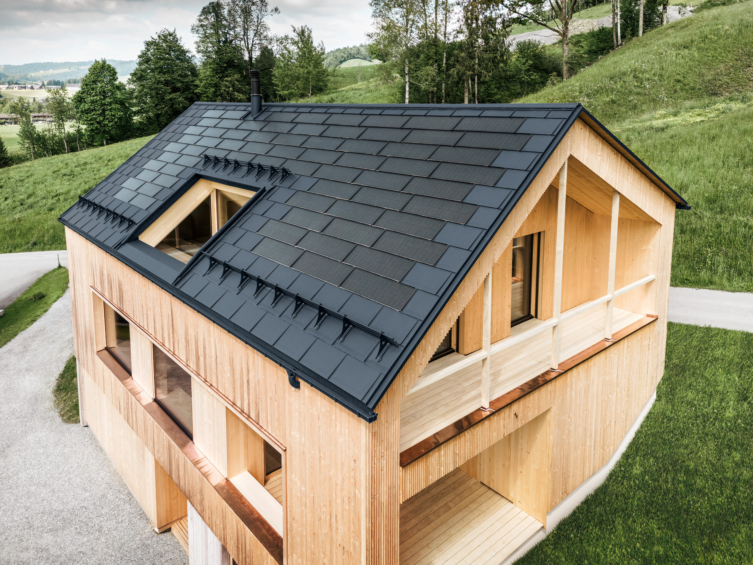 Einfamilienhaus im österreichischen Ort Egg mit der PREFA Solardachplatte und der Dachplatte R.16 in Anthrazit, kombiniert mit einer Holzfassade
