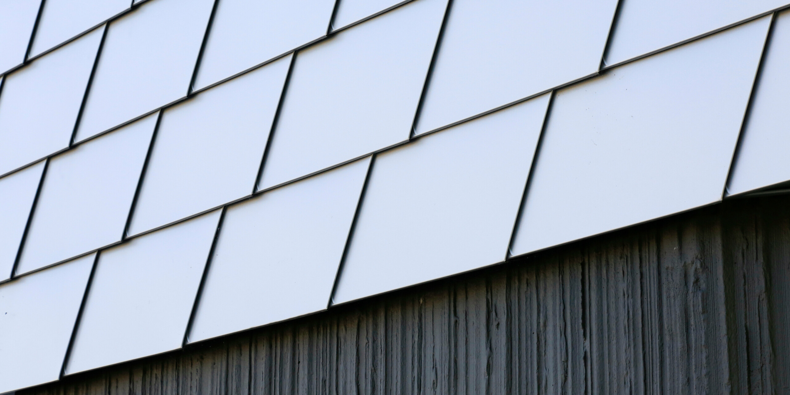 Detailansicht des Gebäudesockels aus Beton und der Fassade aus PREFA Wandschindeln in Silbermettalic am Gesundheitszentrum in Le Landreau