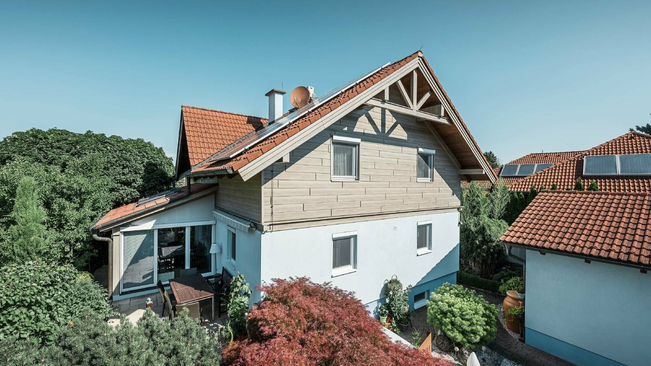 Fassade eines Einfamilienhauses, das im Obergeschoss mit Holzoptik Sidings in der Farbe Eiche beige-grau verkleidet wurde