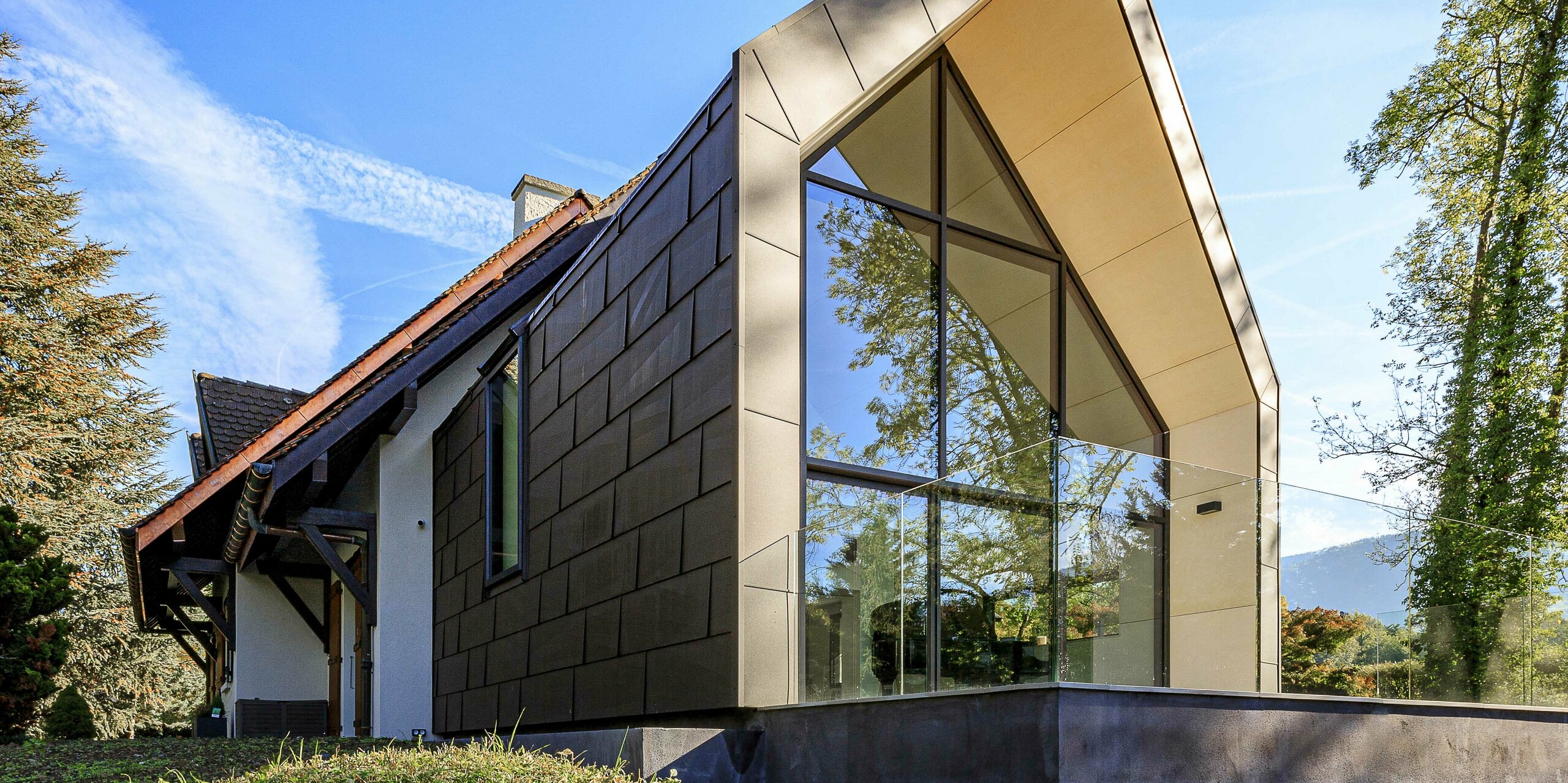 PREFA Dach- und Fassadenpaneele FX.12 in P.10 Braun als kontrastreiches Designelement auf dem Zubau eines Einfamilienhauses in Lully