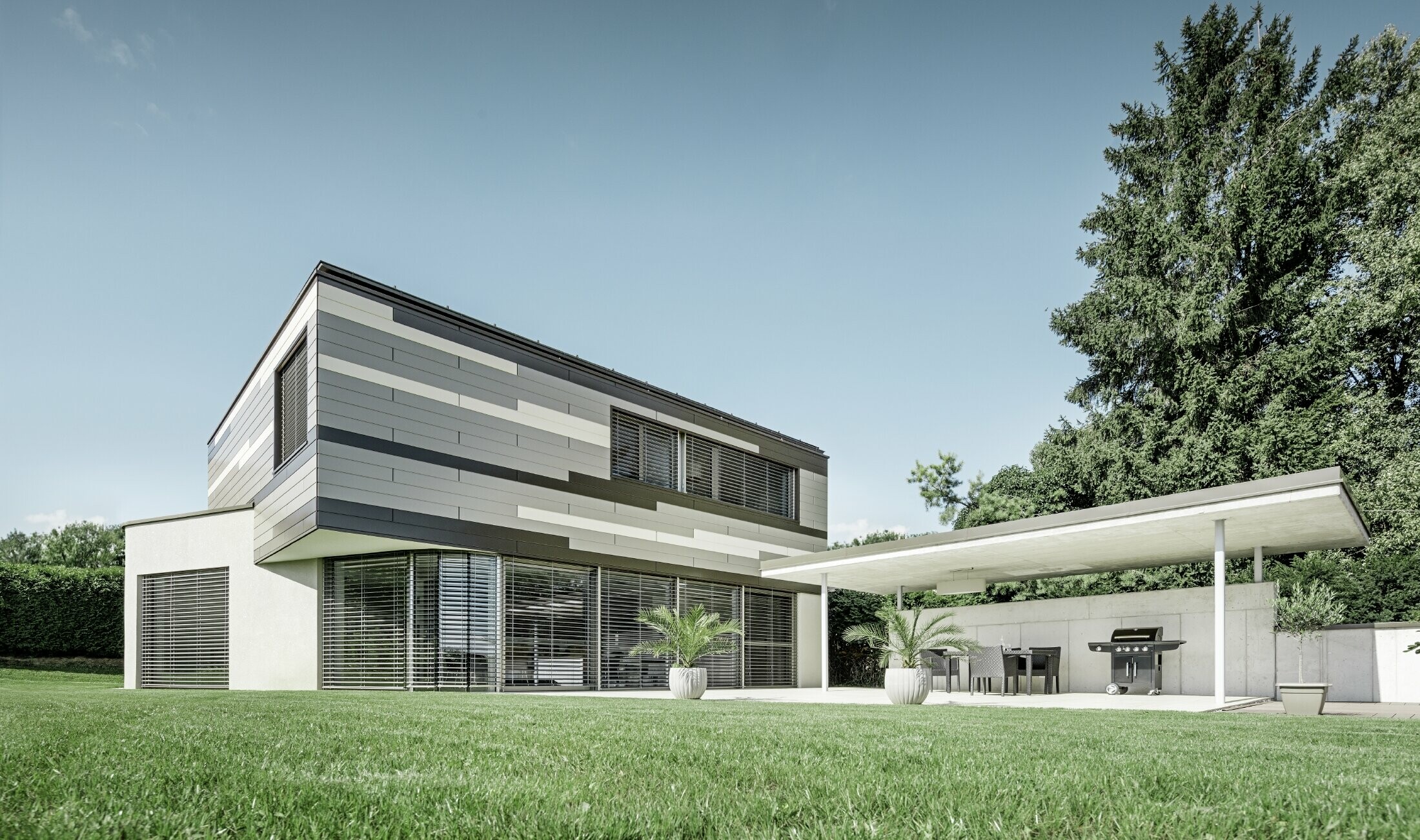 Modernes Einfamilienhaus mit Flachdach und überdachter Terrasse mit einer individuell gestalteten Aluminiumfassade aus Sidings in braun, bronze und elfenbein von PREFA