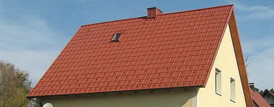 Klassisches Satteldach mit kleinem Dachfenster und Kamin, mit PREFA Dachplatte in Ziegelrot eingedeckt inklusive Schneestoppern und Dachsicherheitshaken.