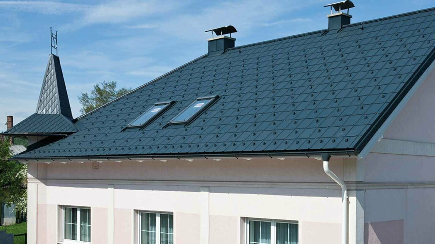 Haus nach der Dachsanierung mit der PREFA Dachplatte in Österreich - zuvor Eternit Faserzement mit Türmchen und rosa Fassade
