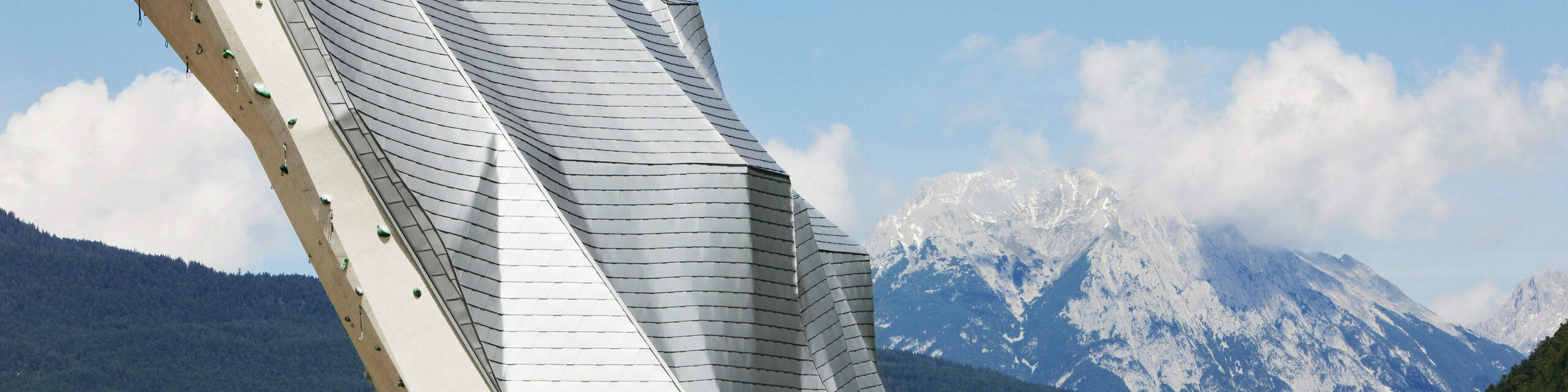 Turmspitze des Kletterturms Imst mit PREFA Aluminiumdach bzw. -fassade in Silbermetallic und schönes Bergpanorama im Hintergrund