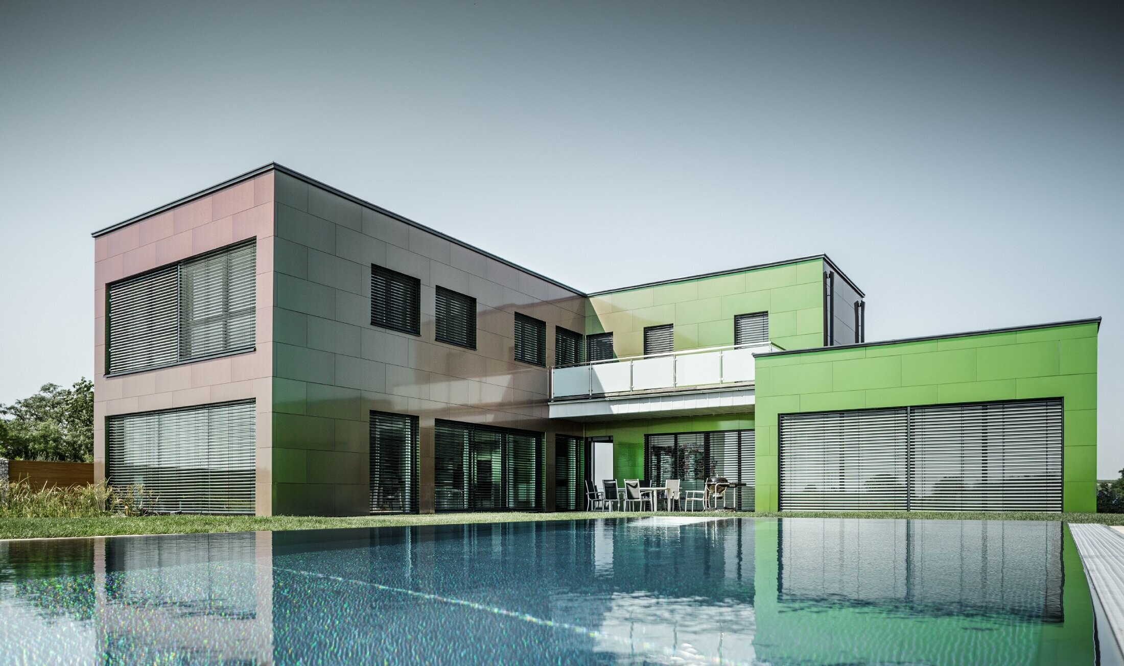 Modernes Einfamilienhaus mit Flachdach uns großem Swimming Pool; Die Fassade ist mit PREFA Aluminium Verbundplatte in der Sonderfarbe Chameleon Spring Lake verkleidet.