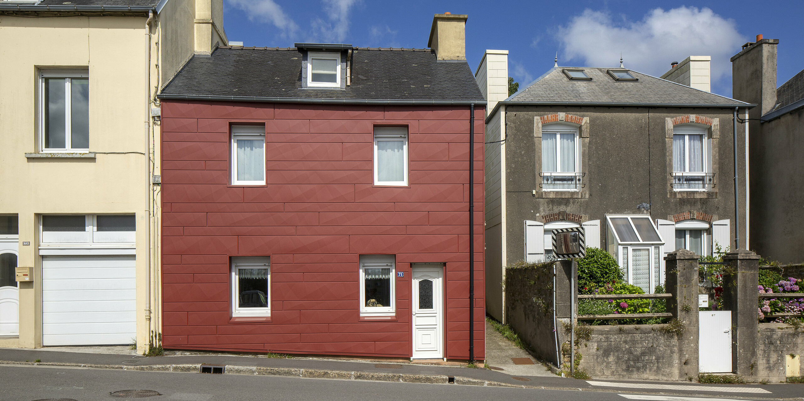 Ein Vorzeigebeispiel für gelungene Fassadensanierung: Das Einfamilienhaus in Brest besticht durch die moderne FX.12 Fassadenpaneele in der Farbe P.10 Oxydrot. Die markante Geometrie und die kräftige Farbe heben das Haus deutlich von der Umgebung ab. Ein langlebiger, wartungsfreier Eyecatcher, der architektonisch neue Akzente in der Straße setzt.