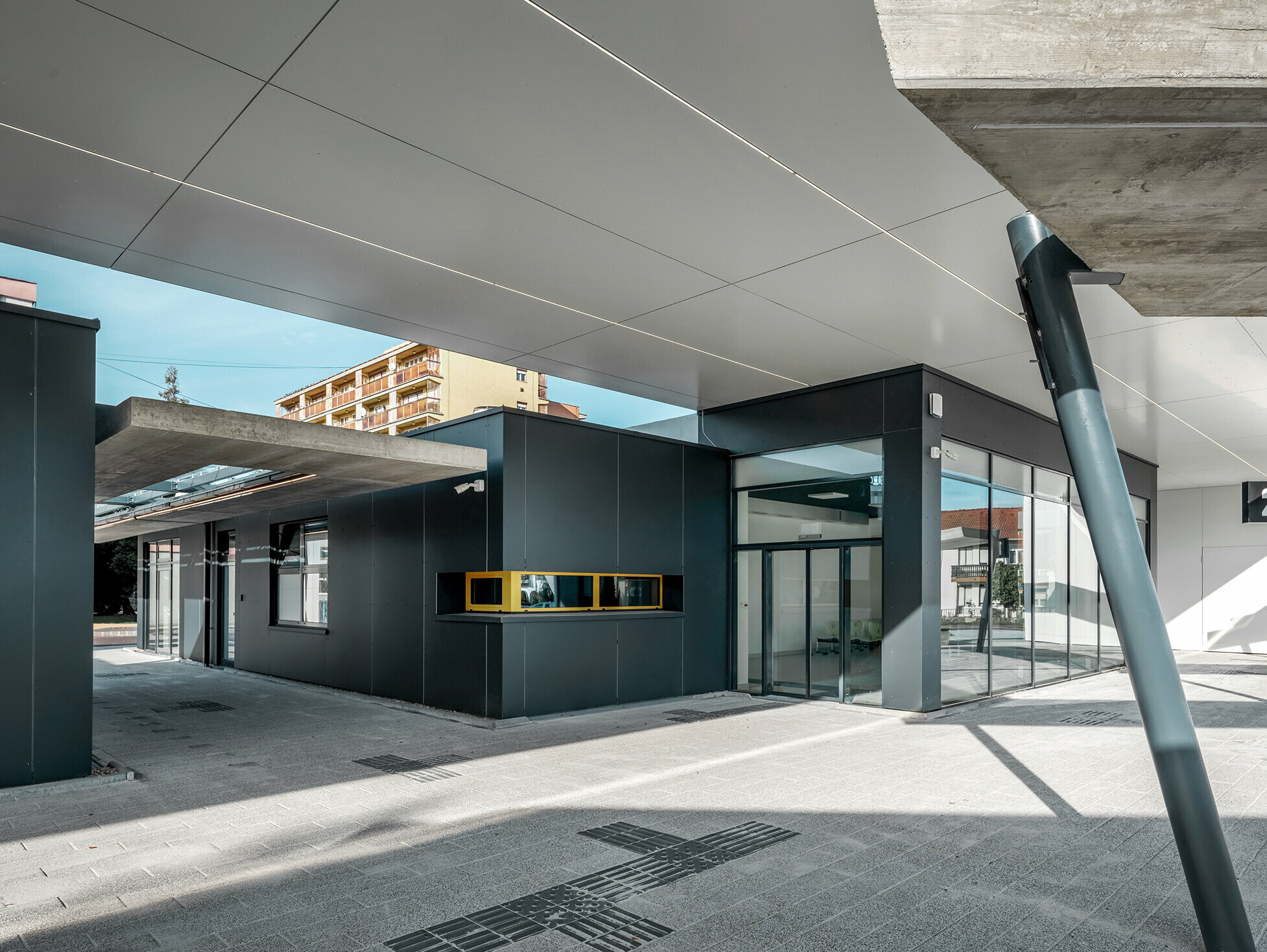 Überdachter Bereich des Busbahnhofs Lenti; Die Untersicht der Überdachung ist mit PREFABOND Verbundplatte in Reinweiß verkleidet, die Fassadenelemente beim Eingangsbereich in P.10 Anthrazit.