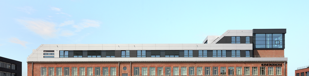 Auf dem Bild ist das Gebäude einsteineins im Wissenschaftspark in Kiel zu sehen. Es hat eine moderne Dachaufstockung mit PREFABOND Aluminium Verbundplatten in Silbermetallic und Anthrazit bekommen.