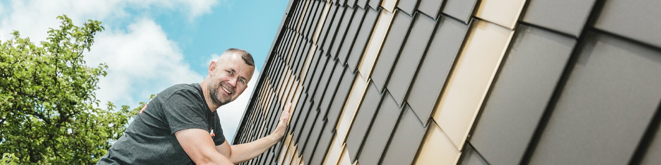 PREFA Handwerker in Ihrer Nähe an einer Fassade mit PREFA Wandrauten in Braun und Mayagold.